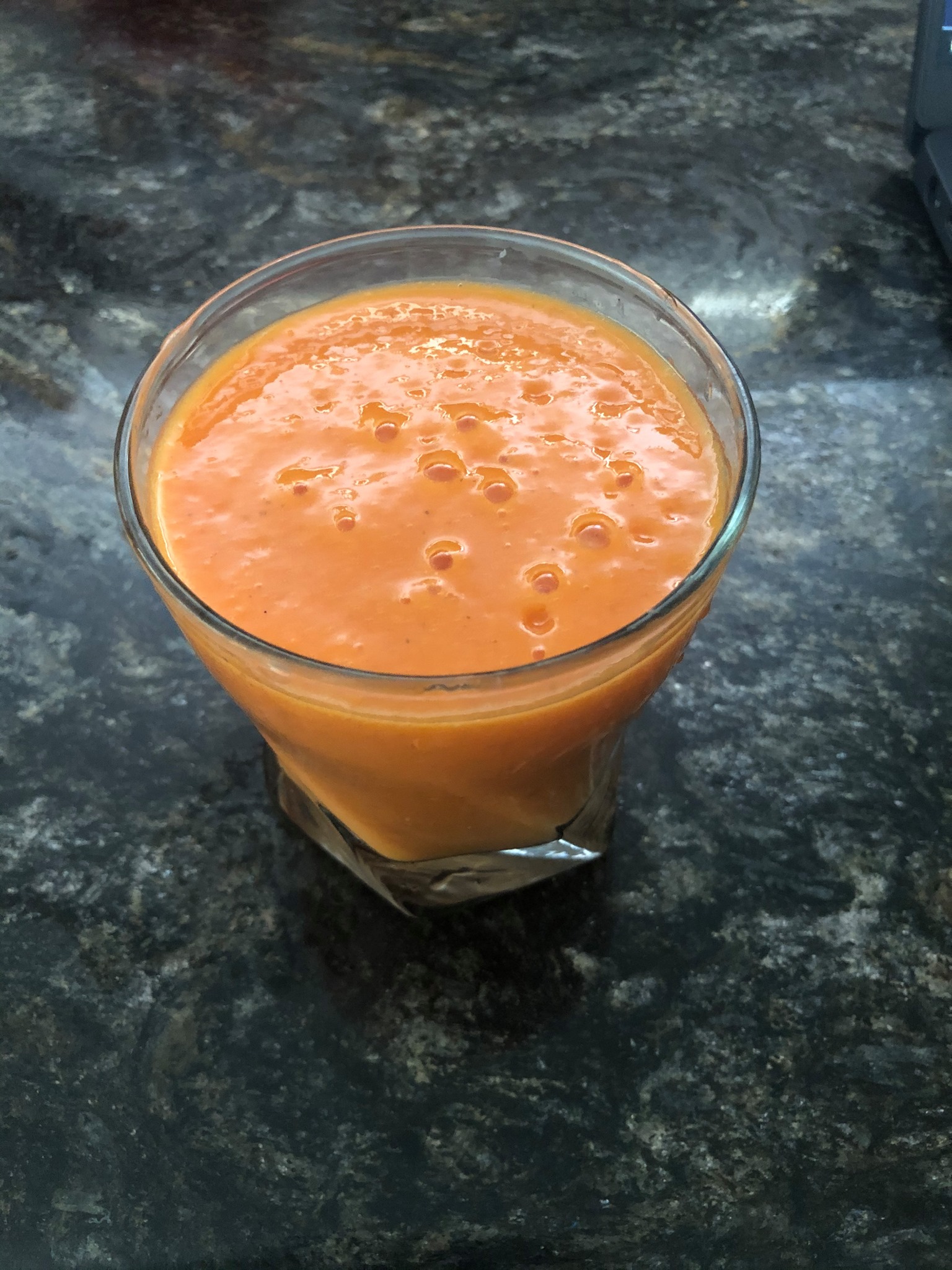 A glass of orange smoothie filled to the brim